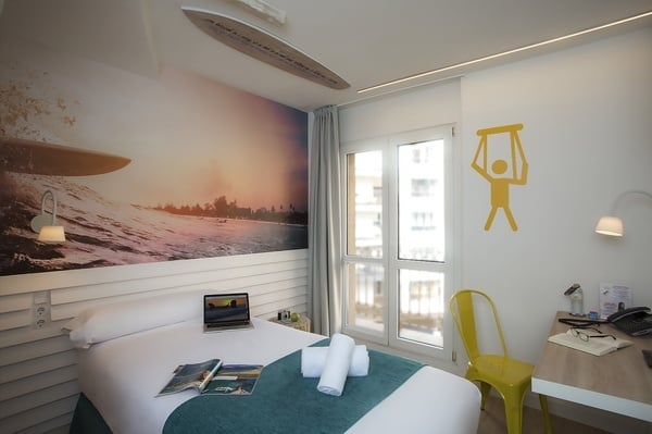 uma cama em um quarto com uma prancha de surf na parede