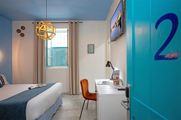 um quarto com uma cama e uma mesa e uma porta azul com o número 2