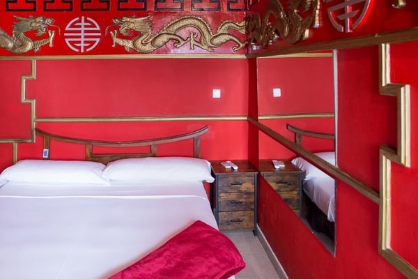 una habitación roja con una cama y un espejo