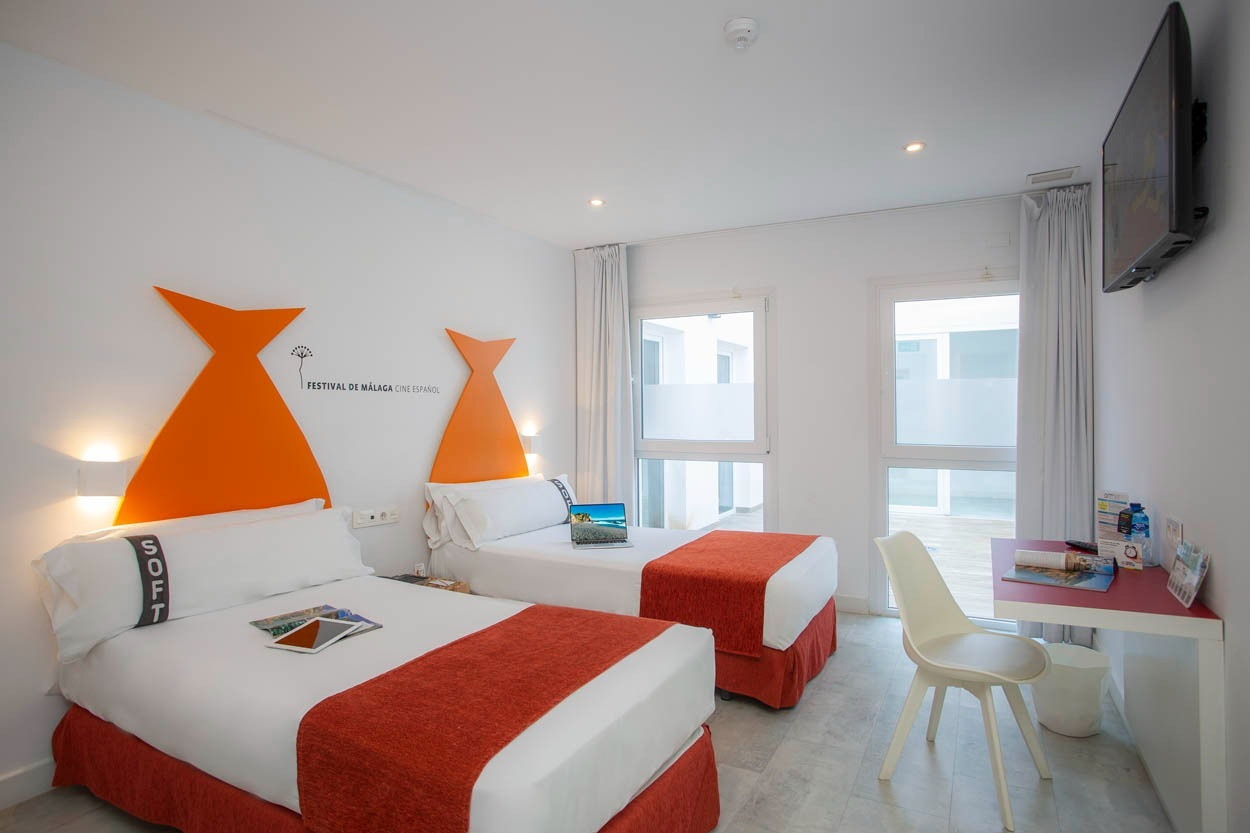 Modernes Hotelzimmer im Casual del Mar Málaga mit zwei Einzelbetten, Schreibtisch und TV.