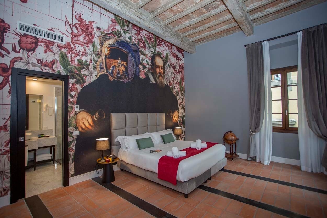 Elegantes Schlafzimmer im Casual Rinascimento Firenze, mit auffälliger Wandkunst, Himmelbett und antiker Dekoration.