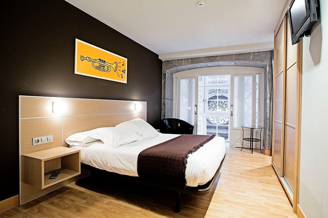 Komfortables Doppelbett mit brauner Decke im Casual Arriaga Bilbao - Hotel nahe Arriaga-Theater. Offizielle Website von Casual Hoteles.