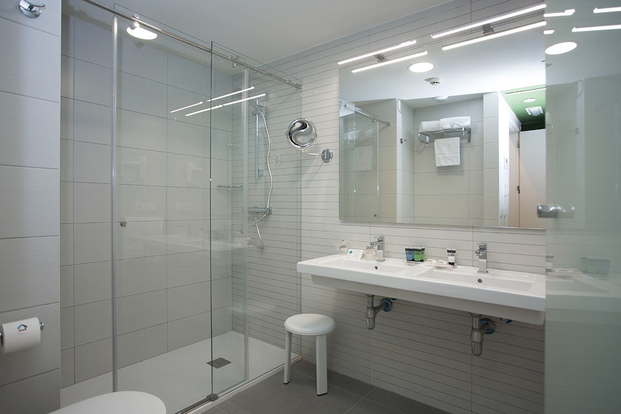 Modernes Badezimmer mit Doppelwaschbecken und Dusche im Casual de las Olas San Sebastián – Themenhotel in San Sebastián | Casual Hoteles.