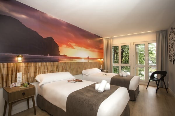 um quarto com duas camas e um pôr do sol na parede