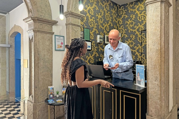 a woman stands at a counter talking to a man in a hotel