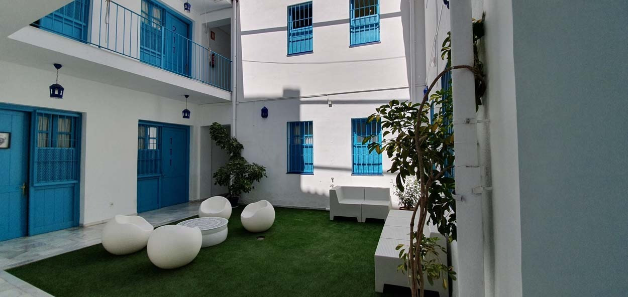 Innenhof mit Lounge-Möbeln und türkisfarbenen Akzenten, Casual de las Letras Sevilla Hotel.