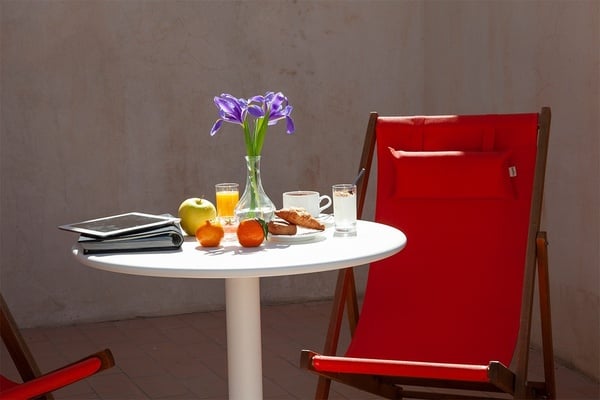 une chaise longue rouge est assise à côté d' une table avec des fruits et des boissons