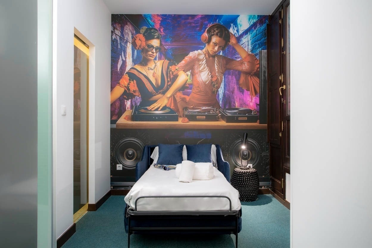 Cama abatible azul y mural vibrante de DJ en Casual Ilbira Granada, hotel boutique céntrico.