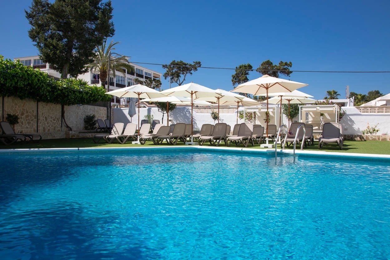 Piscine d'hôtel Casual Bahía Ibiza avec chaises longues et parasols, près de la plage d'Ibiza.