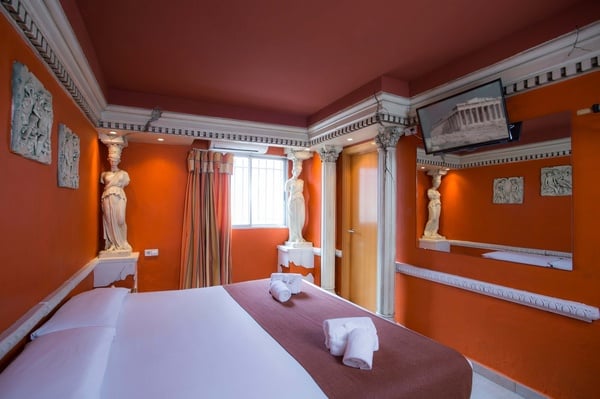 una habitación naranja con una cama y una televisión