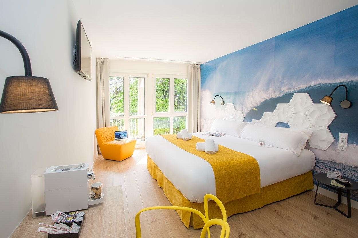 Modernes Hotelzimmer mit Wellen-Wandbild & gelben Akzenten, Casual de las Olas San Sebastián – Themenhotel