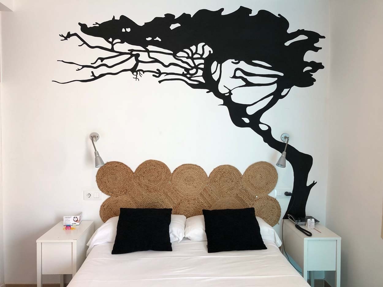 Gemütliches Schlafzimmer mit Baumwandkunst und Jute-Kopfteil im Casual de las Letras Sevilla.