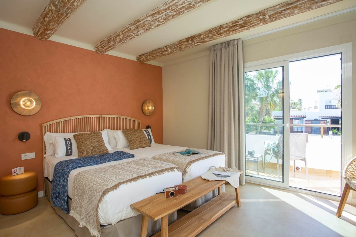 Chambre d'hôtel Casual Bahía Ibiza avec 2 lits, vue sur la plage et poutres apparentes.