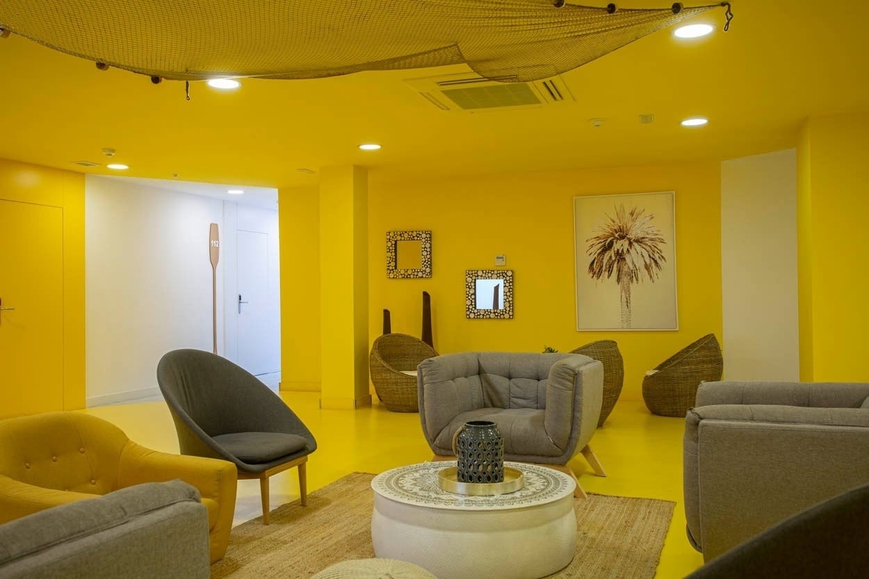 Lobby: Gemütliche Sitzecke mit gelben Wänden und Kunstwerk. Casual del Mar Málaga - Ihr Hotel nahe dem Meer.