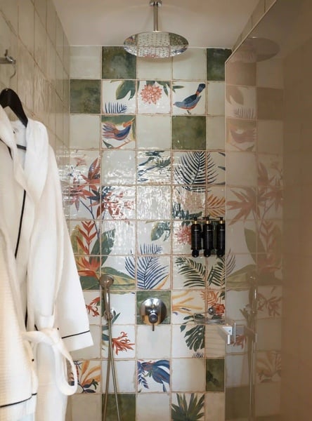 een witte badjas hangt aan een hanger in een badkamer met kleurrijke tegels