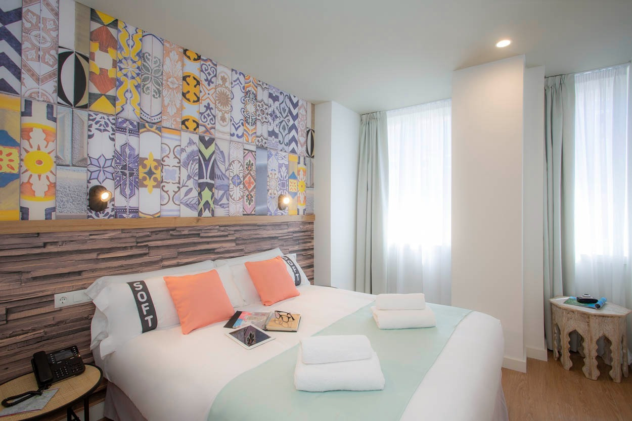 Camera moderna con letto matrimoniale, testiera colorata e arredi unici. Casual Raízes Porto - Boutique Hotel vicino a Santa Catarina.