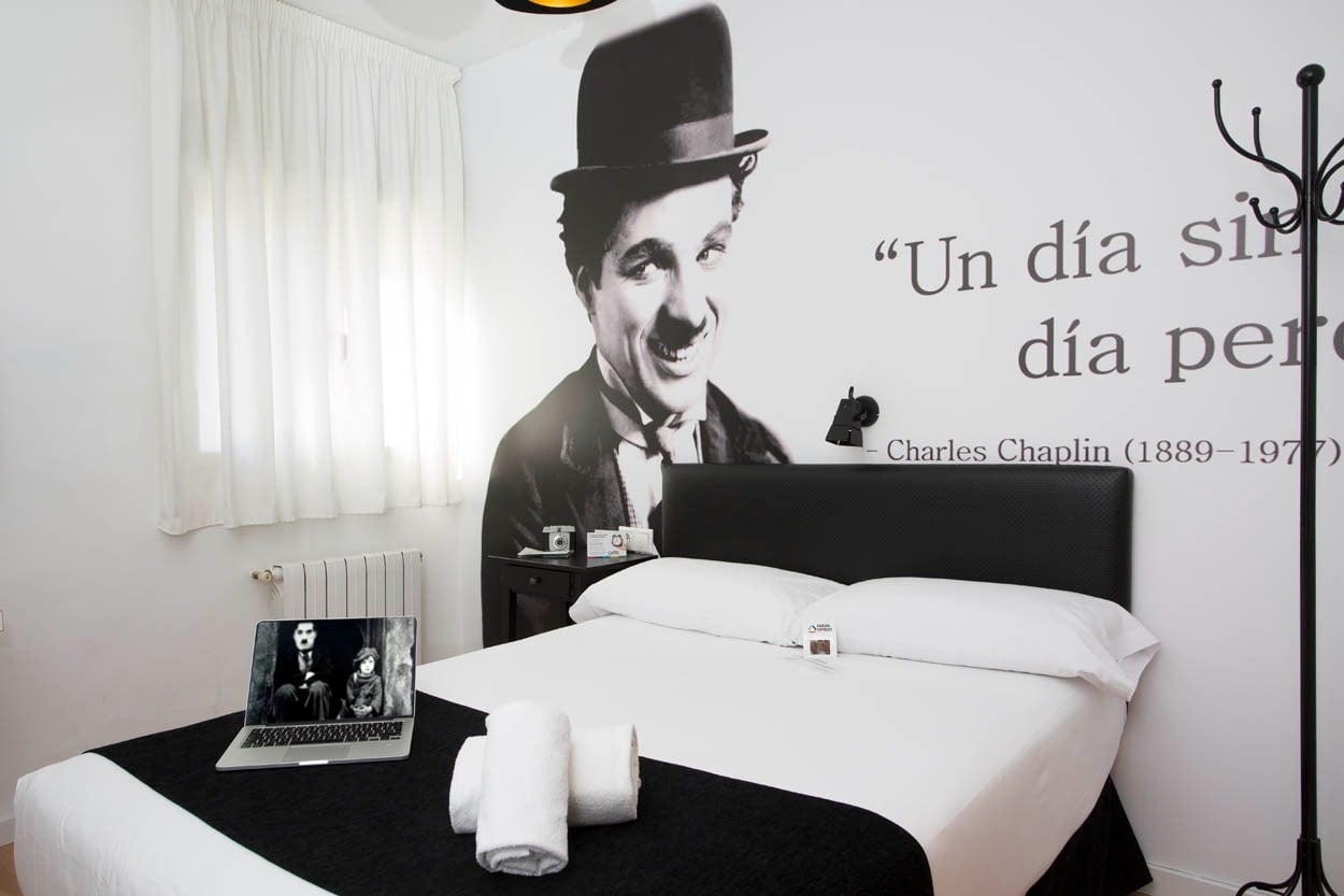 Gemütliches Zimmer im Casual del Cine Valencia - Themenhotel, mit Chaplin-Motiv, Bett, Laptop und Heizung.