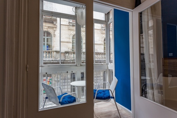 a balcony with two chairs and a table with a blue cushion