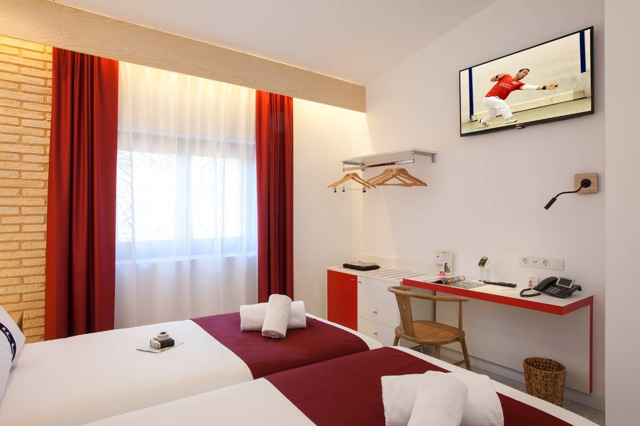 Habitación doble Casual Socarrat Valencia con TV y cortinas rojas, perfecta para tu estancia.