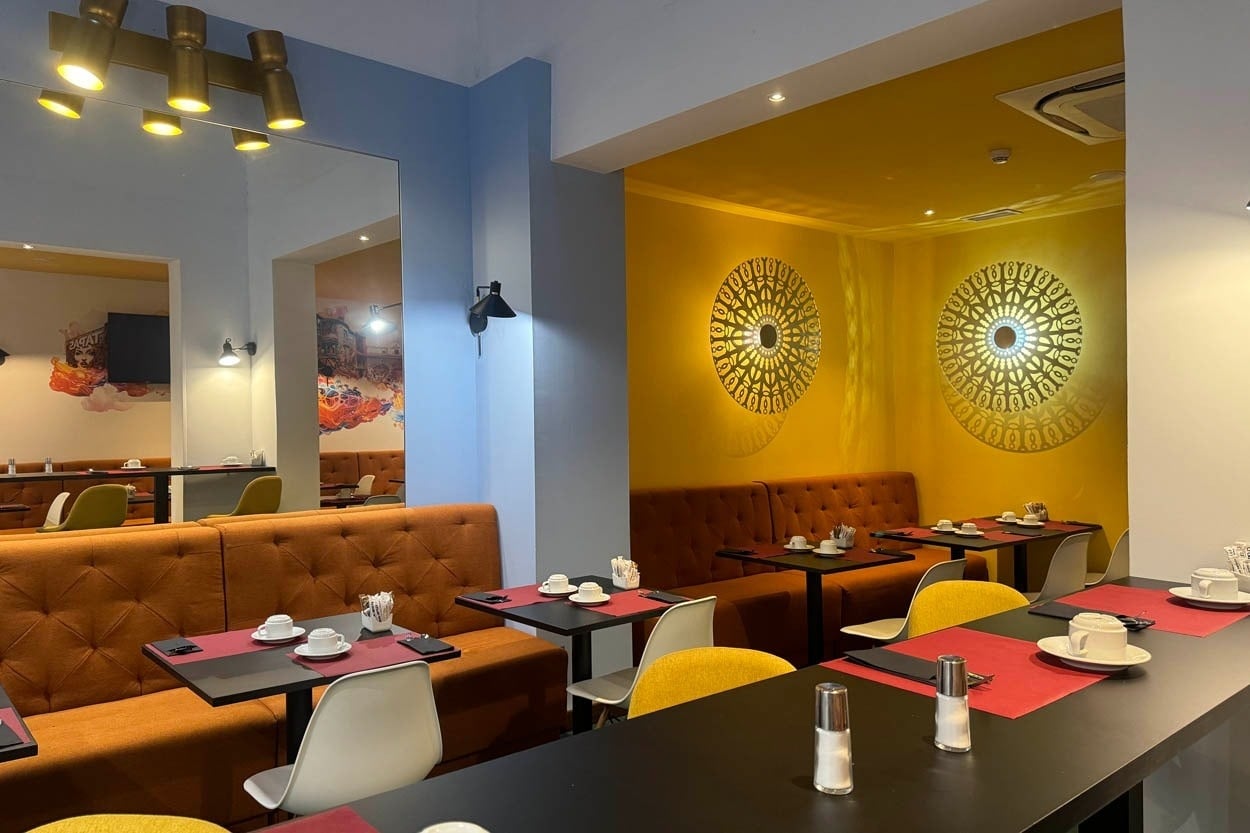 Comedor acogedor en Casual Ilbira Granada con sofás naranjas y arte moderno.