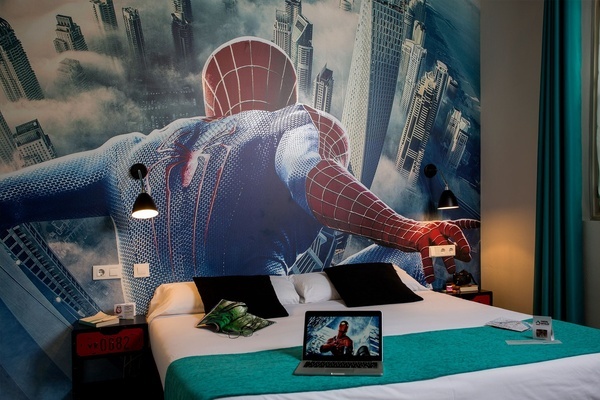 a bedroom with a spider man mural on the wall