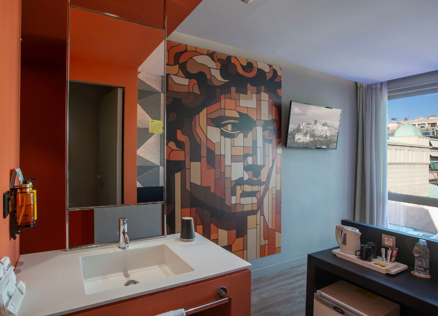 Vibrant hotel room with artistic David mosaic, vanity, TV, minibar, and city view.