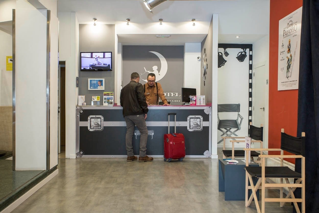 Rezeption im Casual del Cine Valencia: Check-in-Schalter mit Koffern und Sessel im spanischen Stil.
