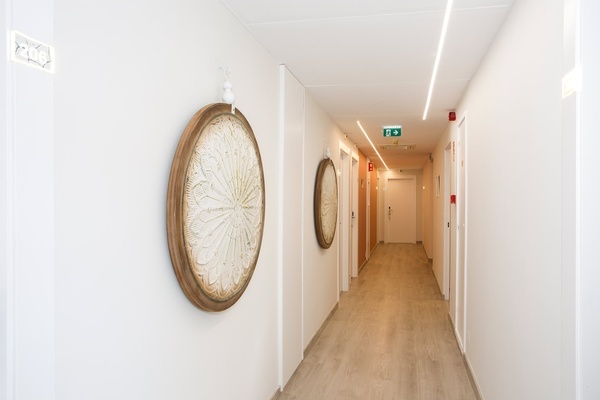 a hallway with a clock on the wall and a green exit sign