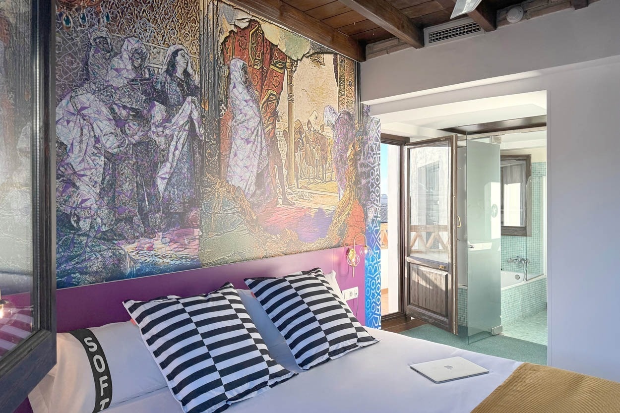Habitación estilo boutique en Casual Ilbira Granada, con mural artístico y baño integrado.