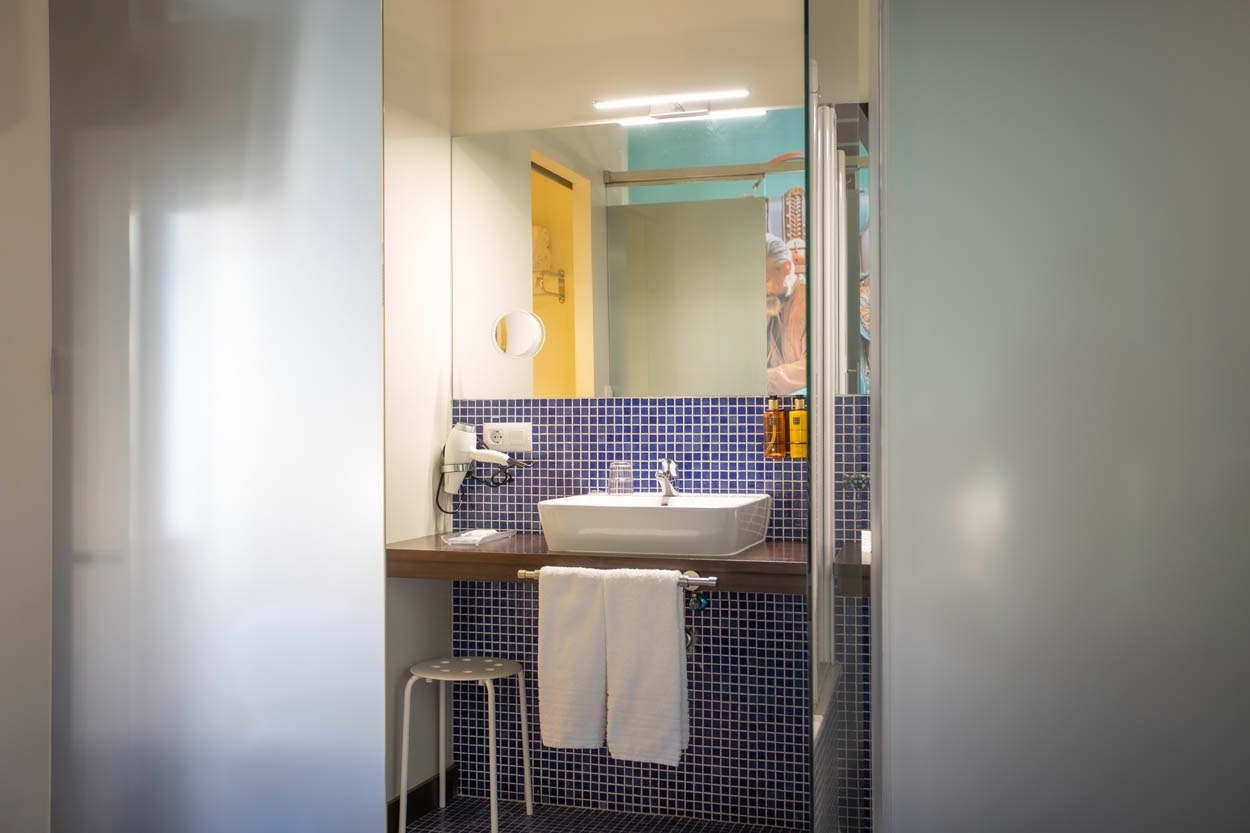 Baño moderno en Casual Ilbira Granada con lavabo, espejo y secador de pelo.