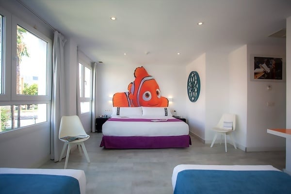 una habitación con dos camas y una pintura de un pez payaso en la pared