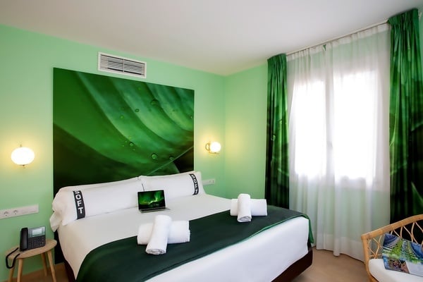 une chambre d' hôtel avec des murs verts et un lit avec un ordinateur portable sur le lit
