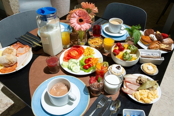 a table topped with plates of food and a jar of milk that says ' fatima hotel ' on it