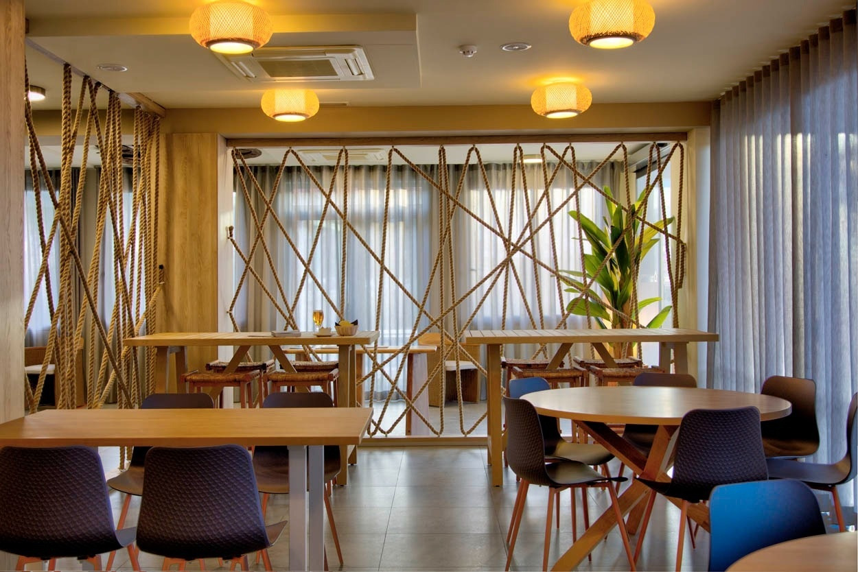 Ambiance décontractée au Casual Bahía Ibiza : salle à manger avec tables en bois, cordes décoratives, près de la plage.