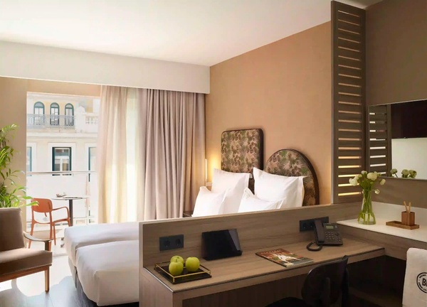 een hotelkamer met twee bedden en een bureau