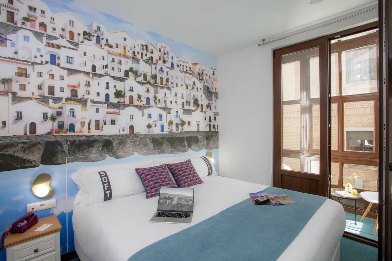 Habitación temática con mural de casas blancas en Casual Ilbira Granada.