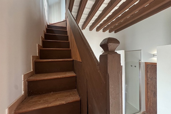 een houten trap leidt naar de tweede verdieping van een huis