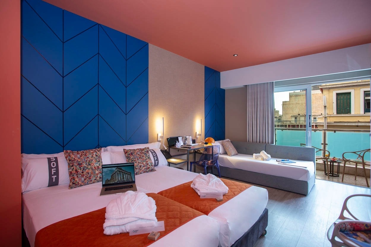 Modernes Hotelzimmer im Casual Kubic Athens mit zwei Betten, Balkon und Blick auf die Stadt.