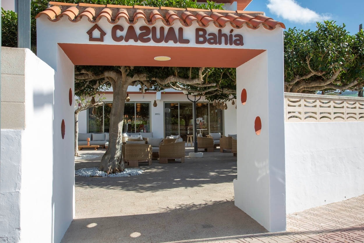 Casual Bahía Ibiza : Entrée d'hôtel moderne avec patio ombragé, mobilier confortable, près de la plage.