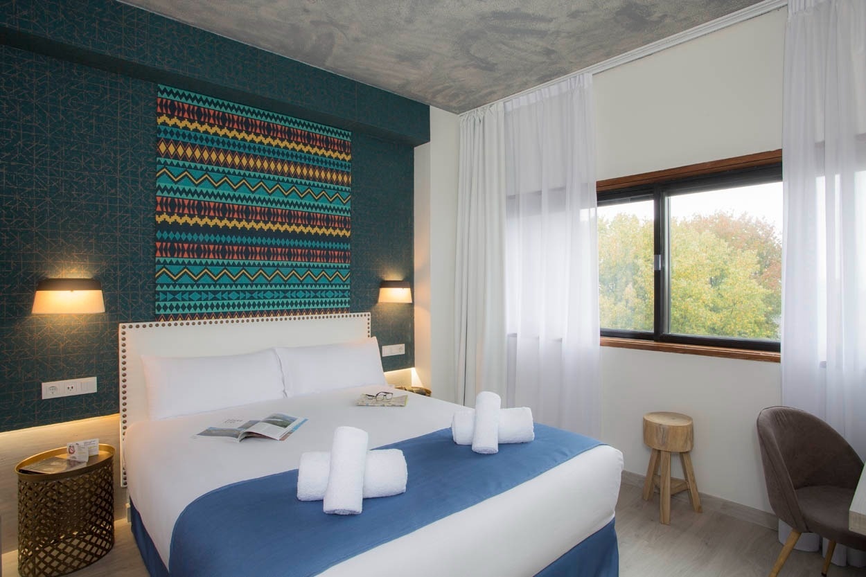Modernes Hotelzimmer im Casual Inca Porto mit bunter Wanddeko und Tageslichtfenster.