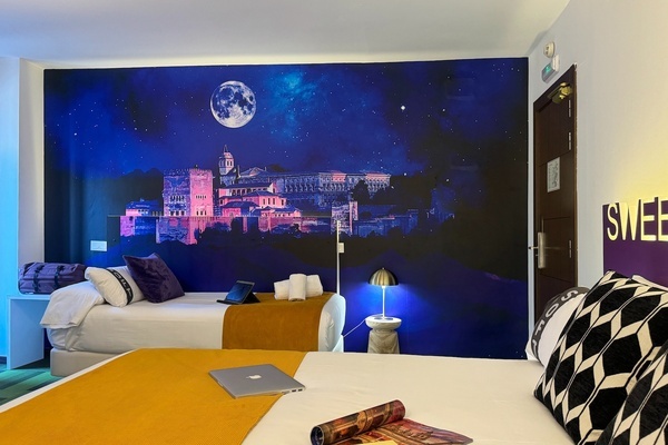 um quarto de hotel com duas camas e uma pintura de uma cidade à noite