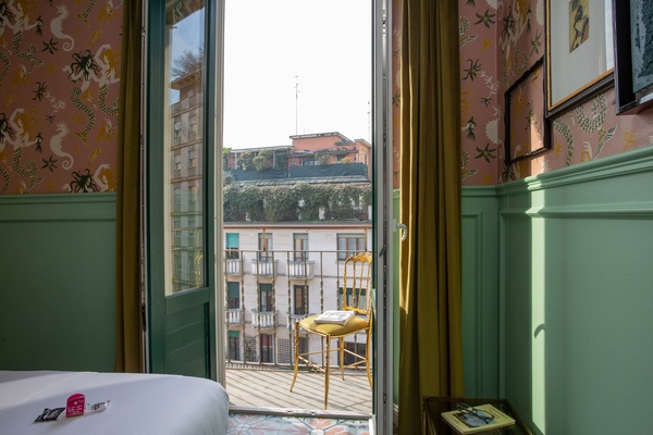 una habitación con una cama y una silla y una puerta que da a un balcón