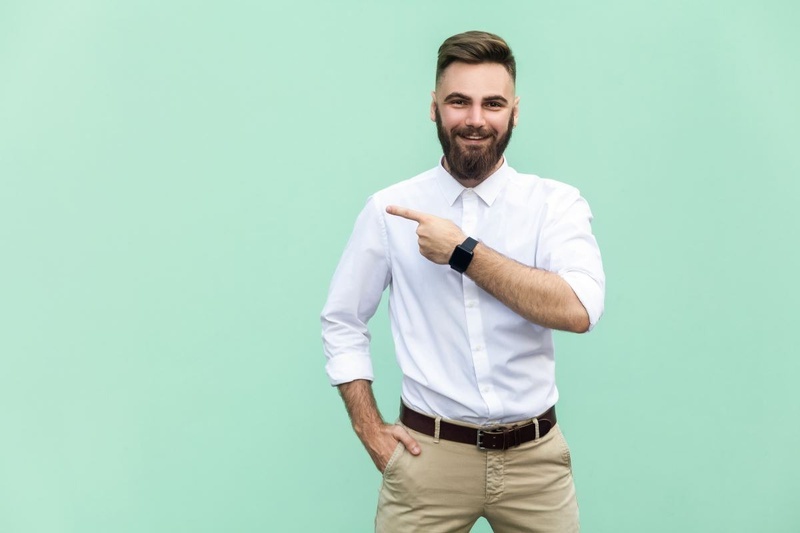 um homem com barba e camisa branca está apontando para o lado