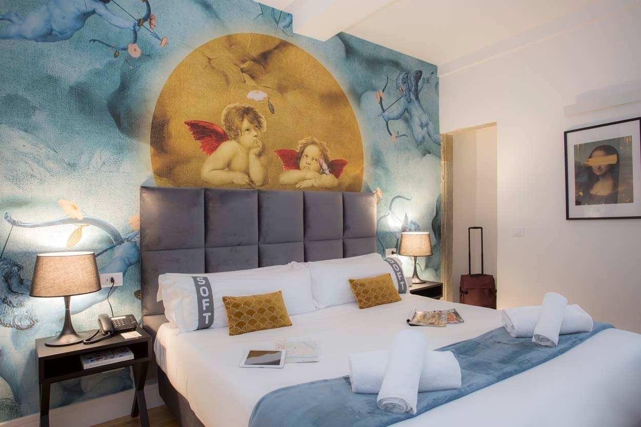 Casual Rinascimento Firenze: Luxuriöses Hotelbett mit Wandgemälde von Putten, ideal für zentralen Aufenthalt in Florenz.