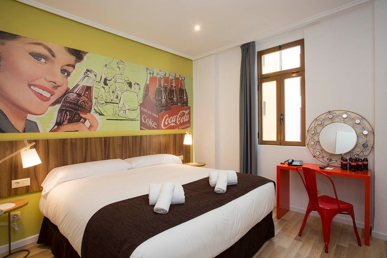 Habitación temática Coca-Cola Casual Vintage Valencia: cama cómoda, escritorio y decoración retro.