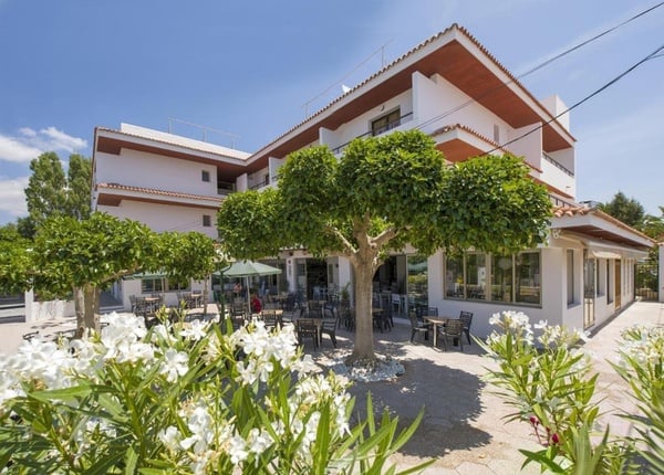 un grand bâtiment blanc avec des tables et des chaises à l' extérieur