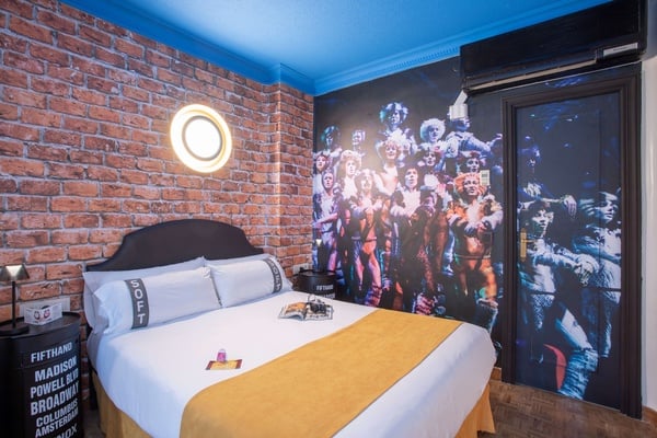 een slaapkamer met een bed en een foto van de cast van cats