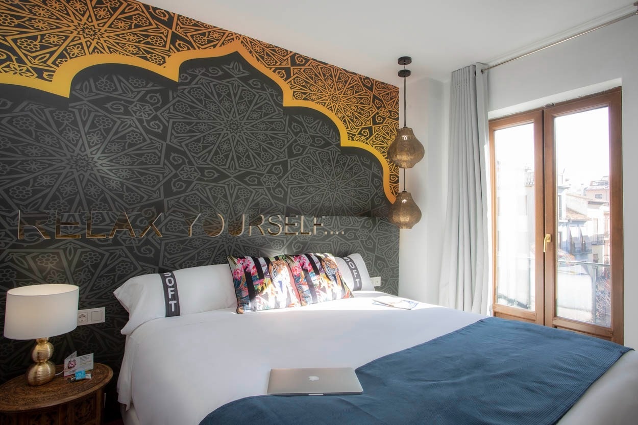 Habitación temática de hotel boutique Casual Ilbira Granada con mural de mandala y comodidades modernas.