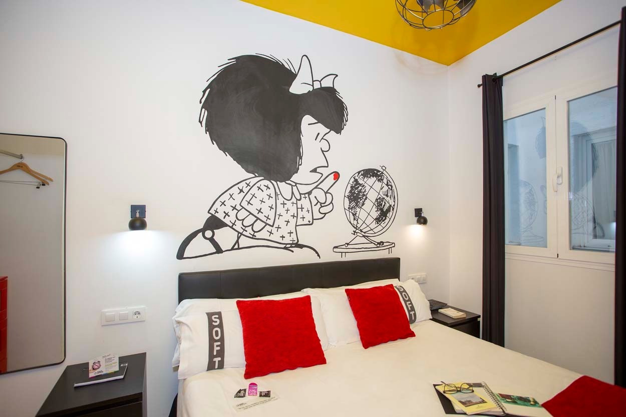 Gemütliches Zimmer im Casual de las Letras Sevilla mit lustiger Wandmalerei und roten Akzenten.