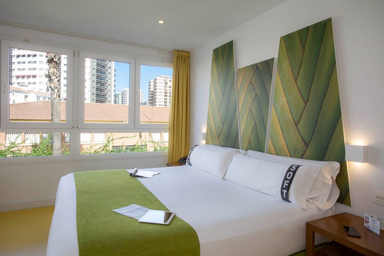 Komfortables Bett mit grünem Überwurf im Casual del Mar Málaga, zentral gelegen in Málaga.
